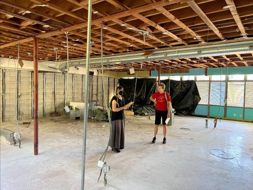 Two people standing in an empty room that is under construction